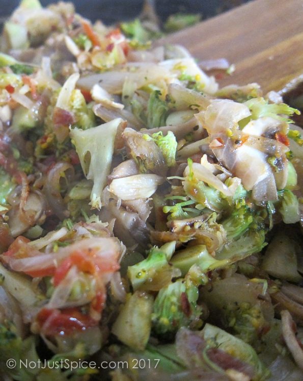 The mushrooms, broccoli, tomatoes, onions and garlic in the skillet for Baked Eggs with Broccoli and Mushroom on notjustspice.com